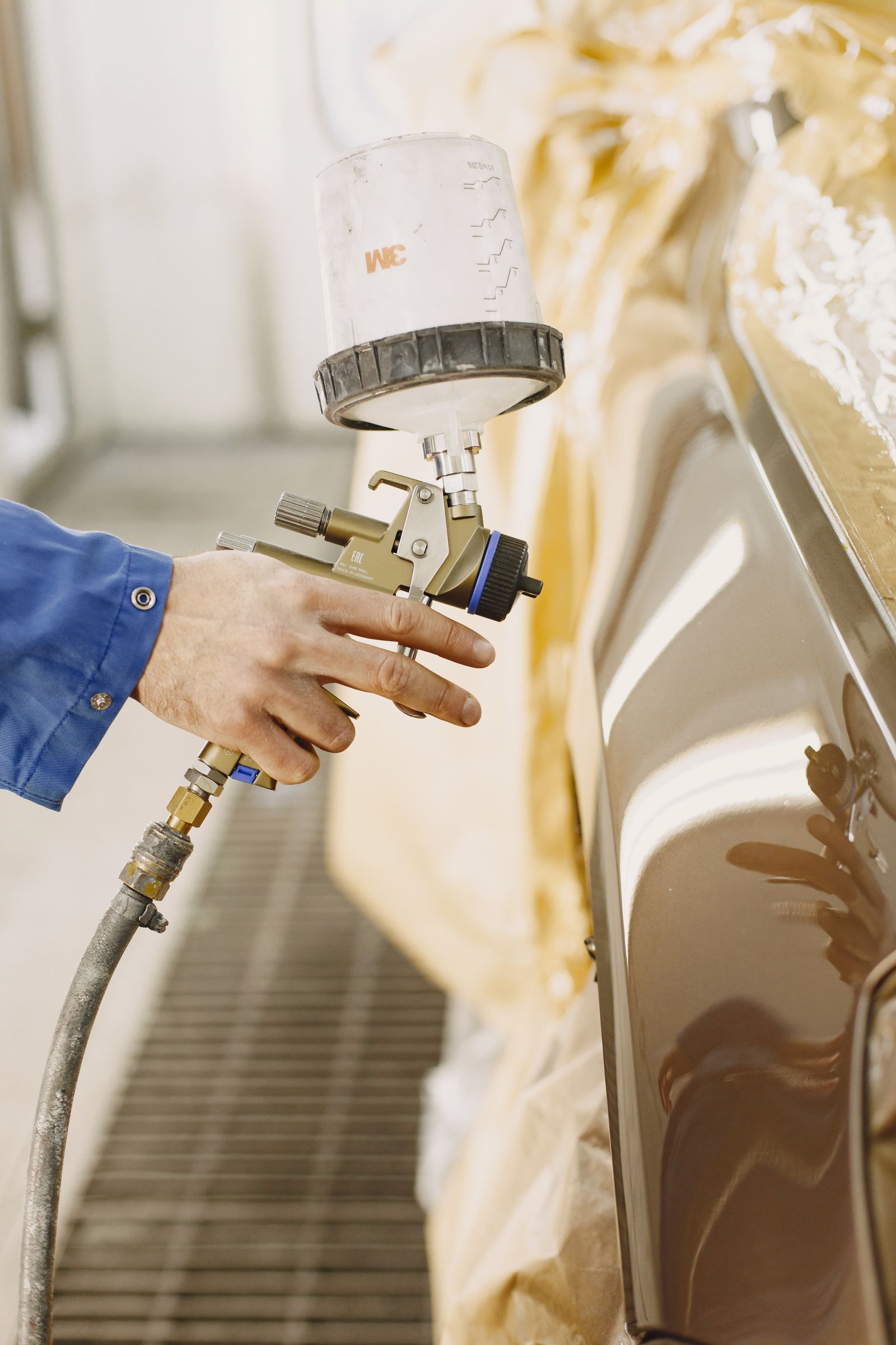 Technician spray-painting a car panel